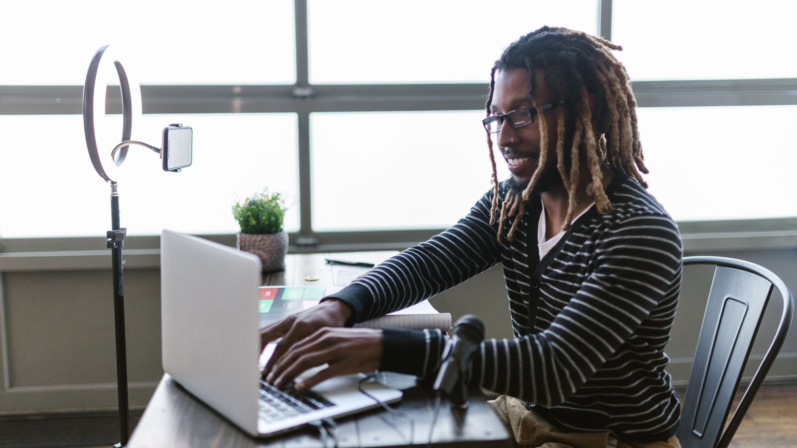Content creator using a laptop with ring light and microphone